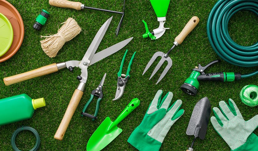 Gardening tools including a rake, trowel, and pruning shears ready for use.